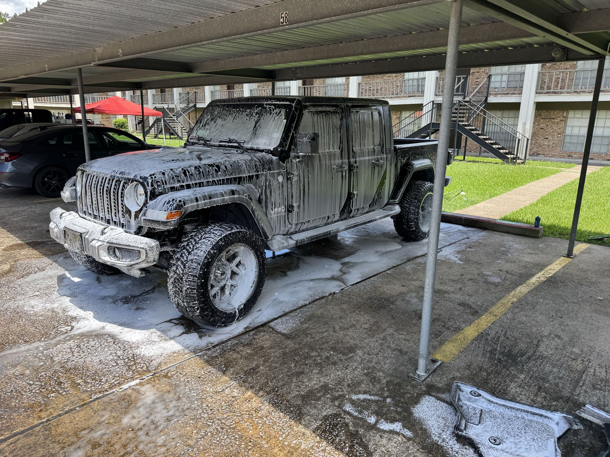 Black Jeep Gladiator covered in foam during a hand wash