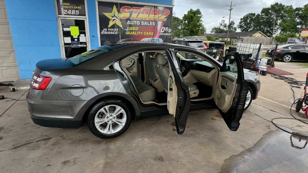 Ford Taurus with all doors open showing clean tan interior